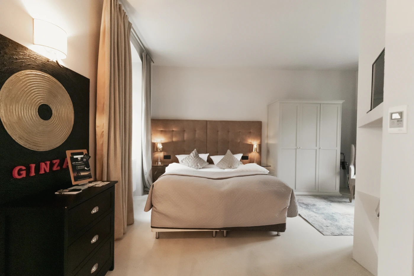 Superior Rooms Hotelzimmer in Heidelberg Neuenheim. Goldenes Doppelbett und schwarzes Sofa.